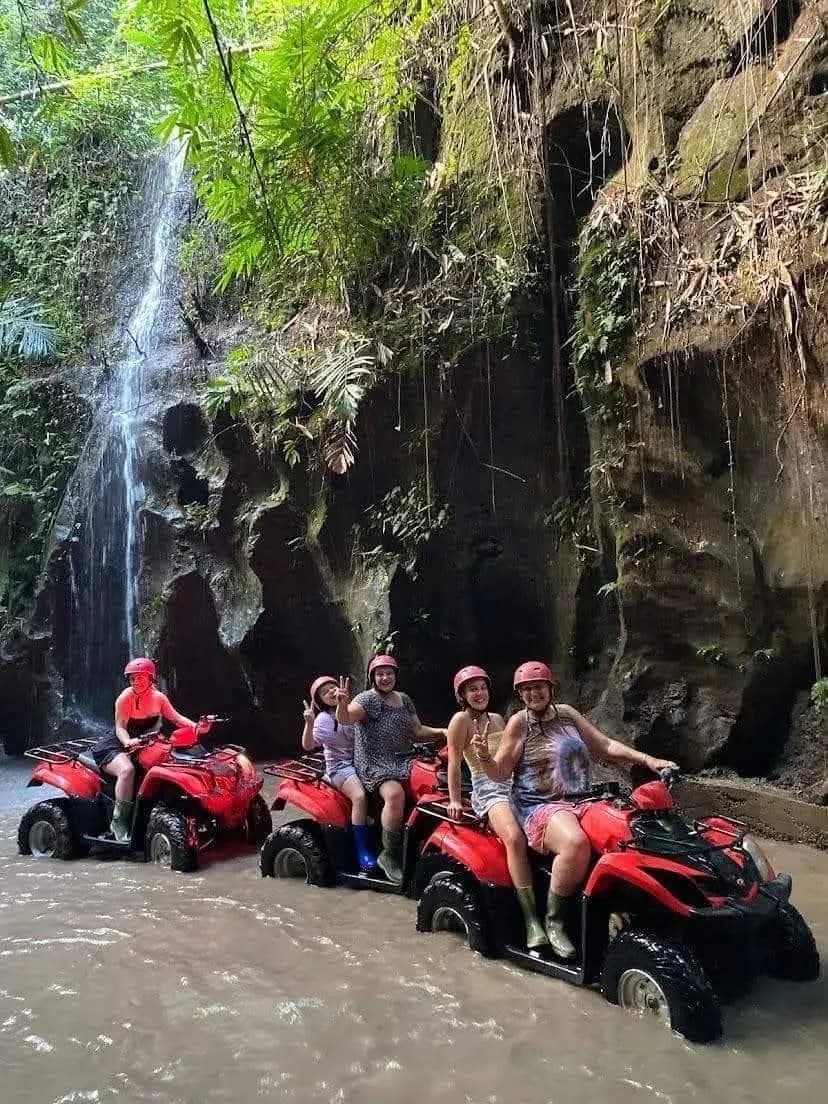 A group of ATV riders stopped at a waterfall