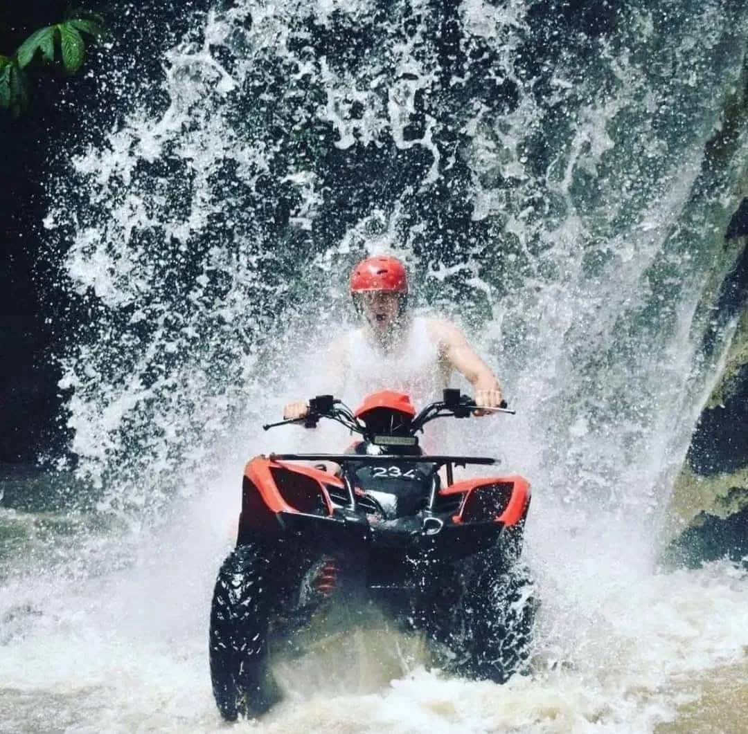 An ATV rider driving straight through a waterfall