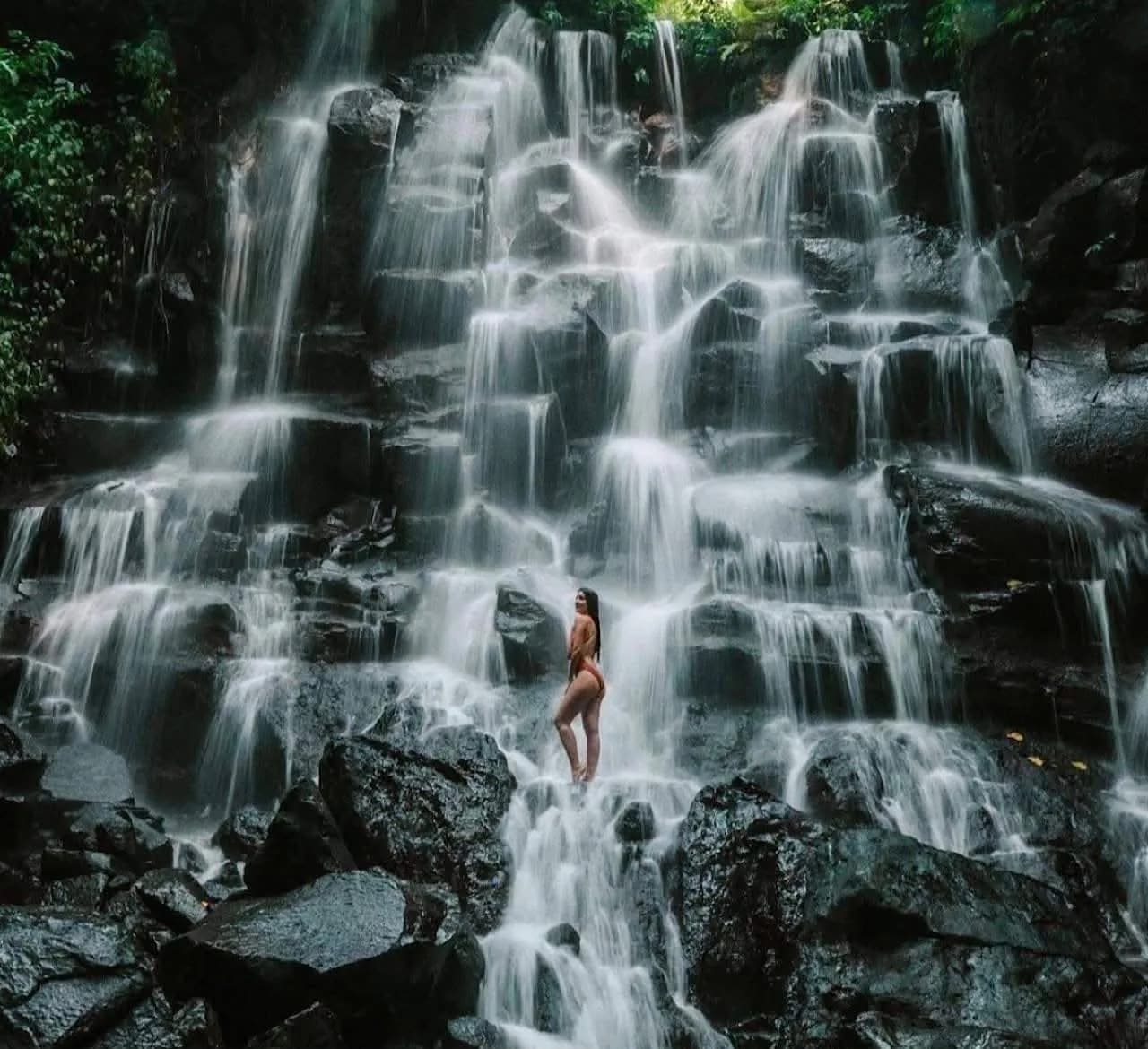 A wide cascade waterfall over dark rock in Bali